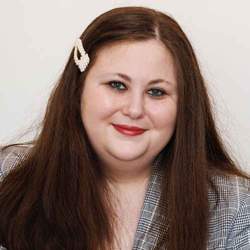 Portrait photo of Marissa Ditkowsky. She has long straight brown hair with a pearl-colored hair barrette on the right. She's wearing a black and white woven suit jacket.