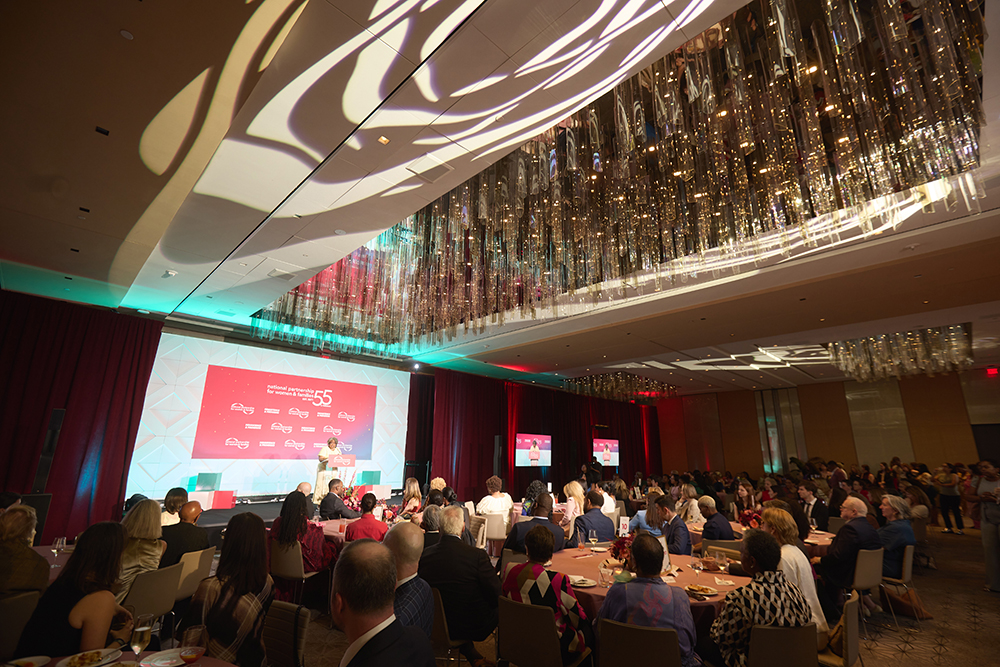 NPWF President Frye in the background on stage with an expansive view of event attendees seated at tables at the 2026 Annual Event