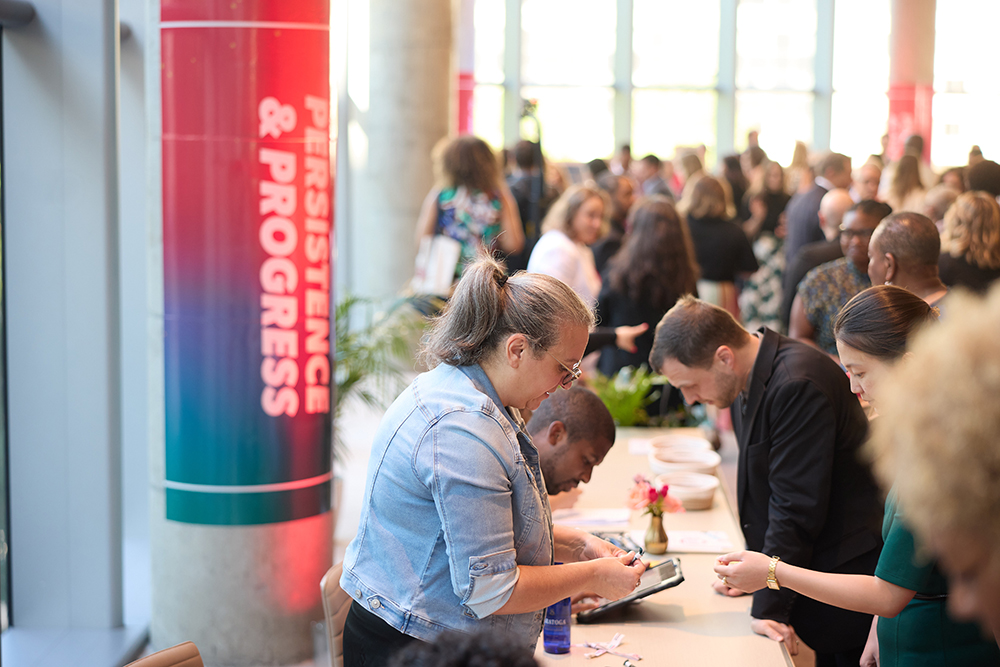 A NPWF staff member checking in attendees at the 2026 Annual Event with a crowd of people in the background