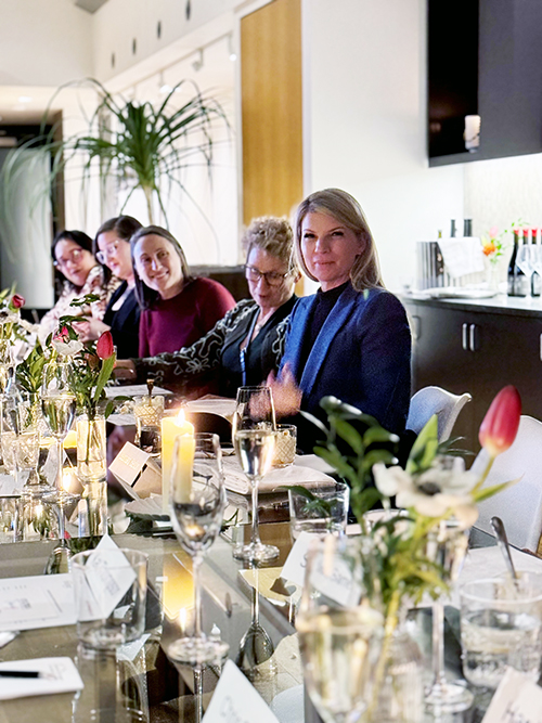 Five women dressed professionally, sitting on one side of a long dinner table during a roundtable with business leaders discussing the FMLA and need for national paid leave