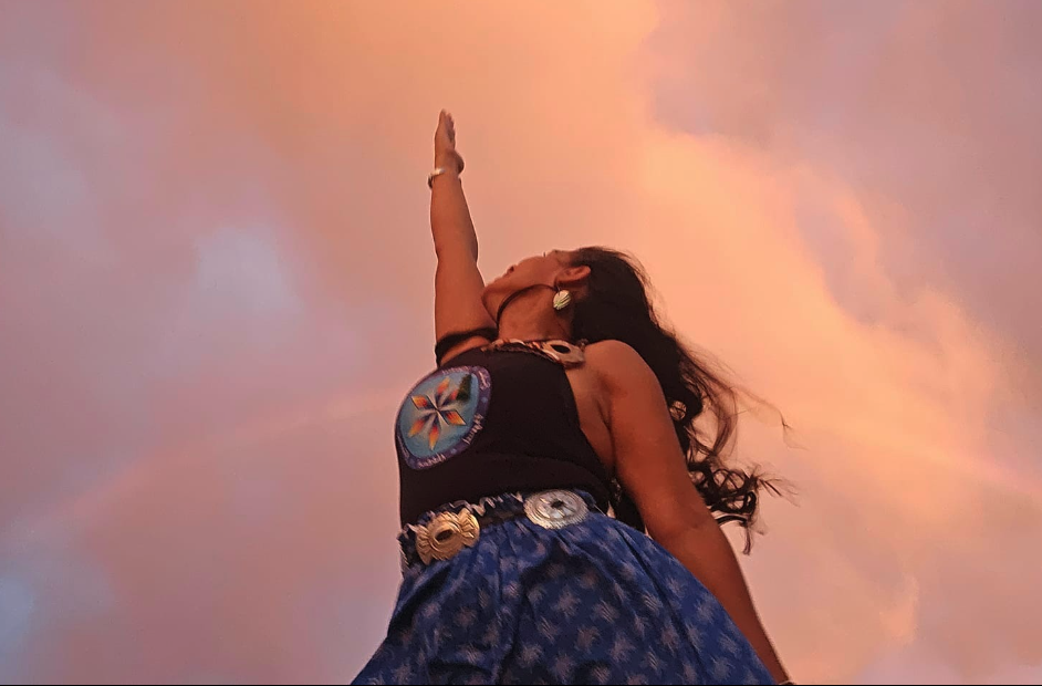 A Native woman in the desert, reaching upward