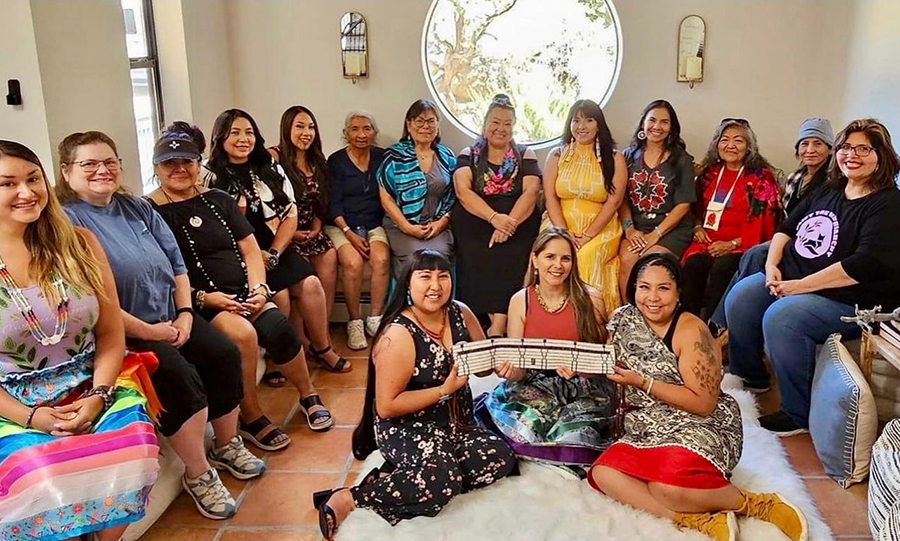A gathering of 16 Native women in a living room.